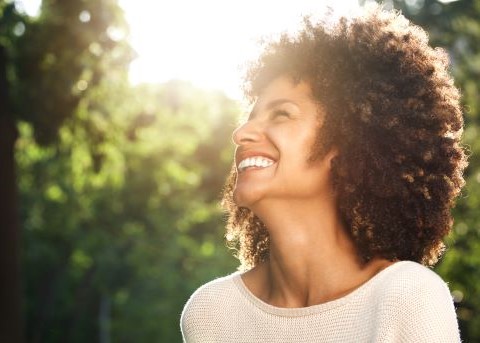 Woman grinning outdoors on sunny day