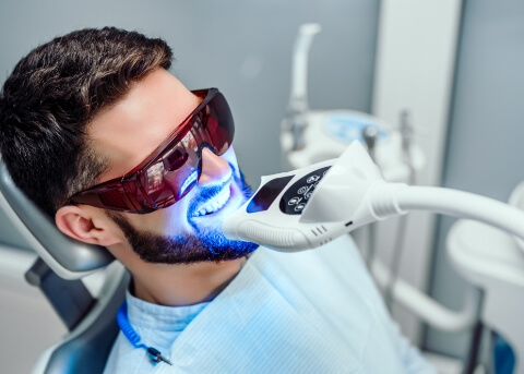 Man in dental chair receiving professional teeth whitening
