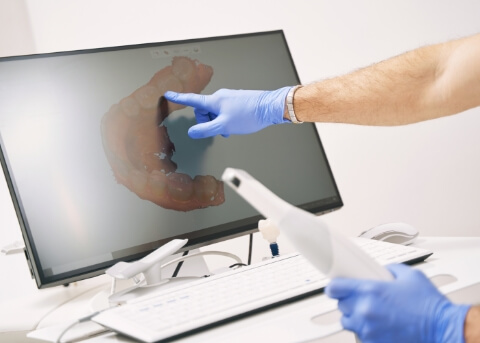 Dentist pointing to computer screen showing digital impressions of teeth