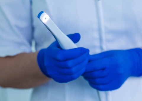 Dental team member holding a white pen like intraoral camera