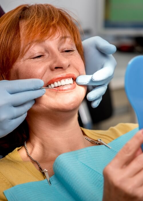 Woman in dental chair looking at her new smile with dental implants in Cumming