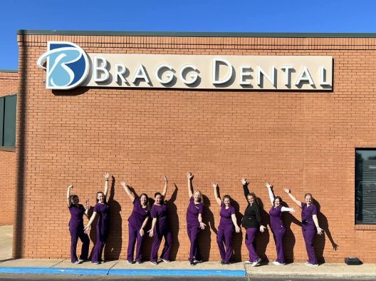 Dental team members in purple scrubs standing outside of Bragg Dental