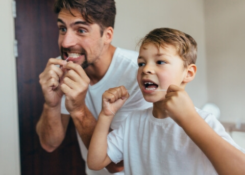 Father and son flossing their teeth together