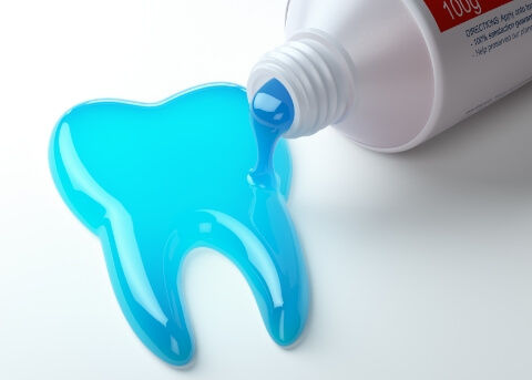 Blue toothpaste spilling out of a tube and into a tooth shape