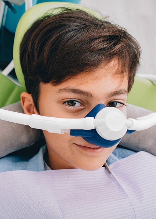 Young boy in dental chair wearing nose mask for nitrous oxide sedation dentistry in Cumming