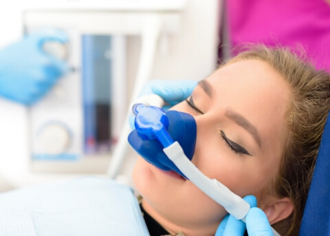 Young woman in dental chair with eyes closed wearing nitrous oxide mask