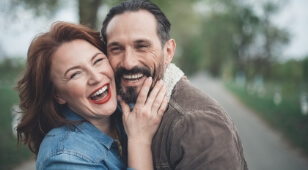 Laughing man and woman hugging outdoors