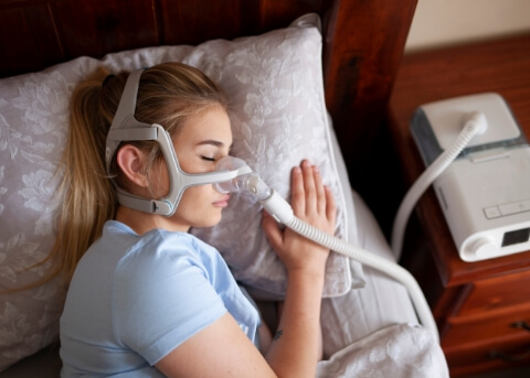 Woman sleeping while wearing a C P A P mask on her face