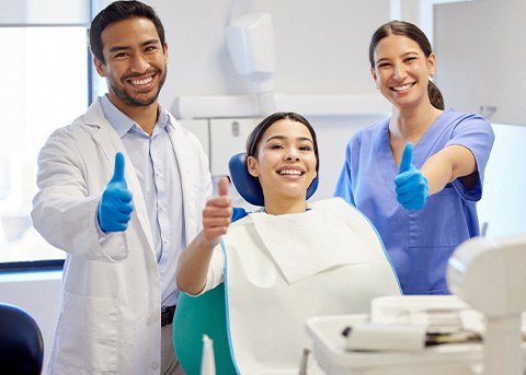 Dentist, dental assistant, and patient giving thumbs up