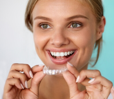 Smiling woman holding a take home teeth whitening tray